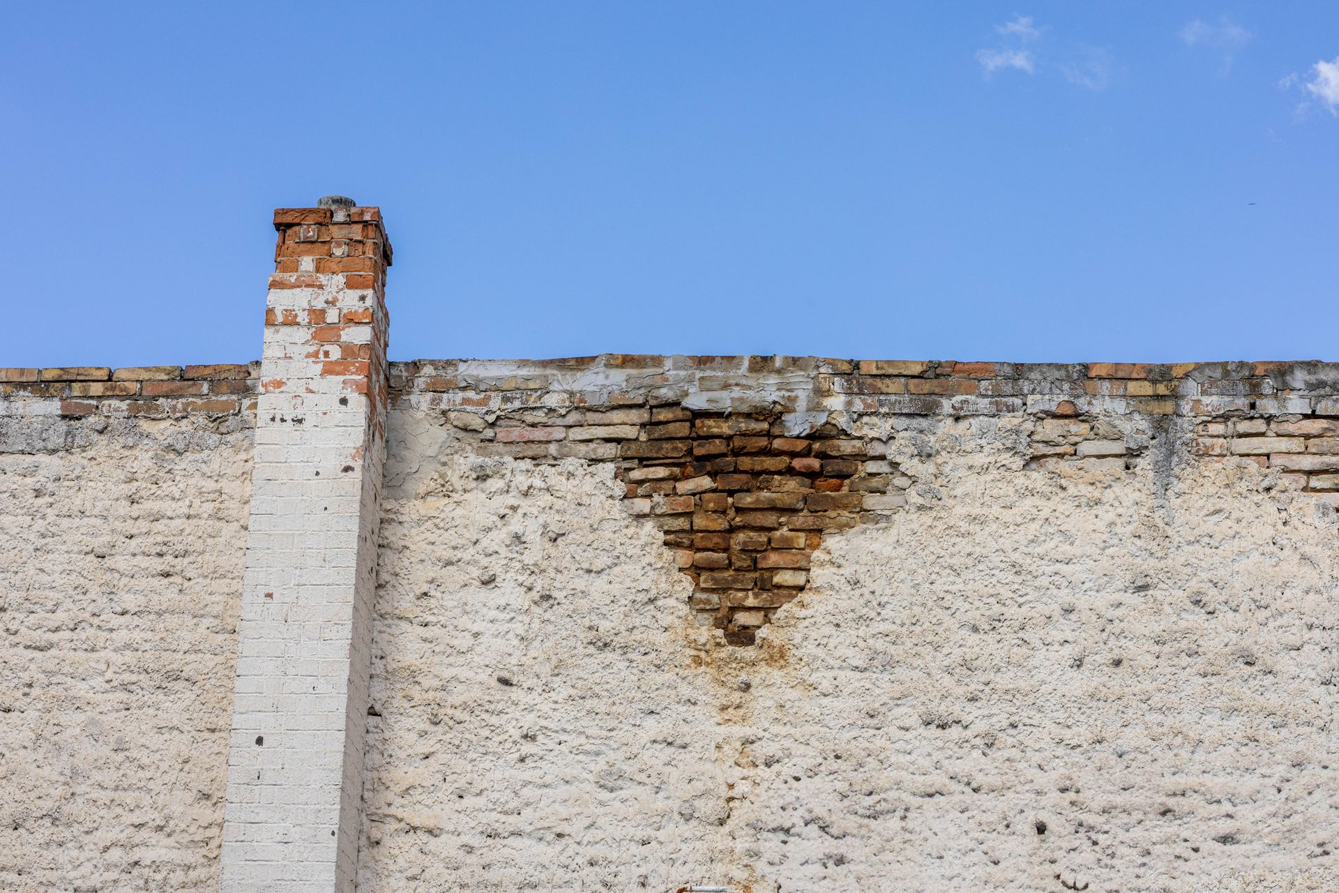Old brick chimney rising against a clear blue sky