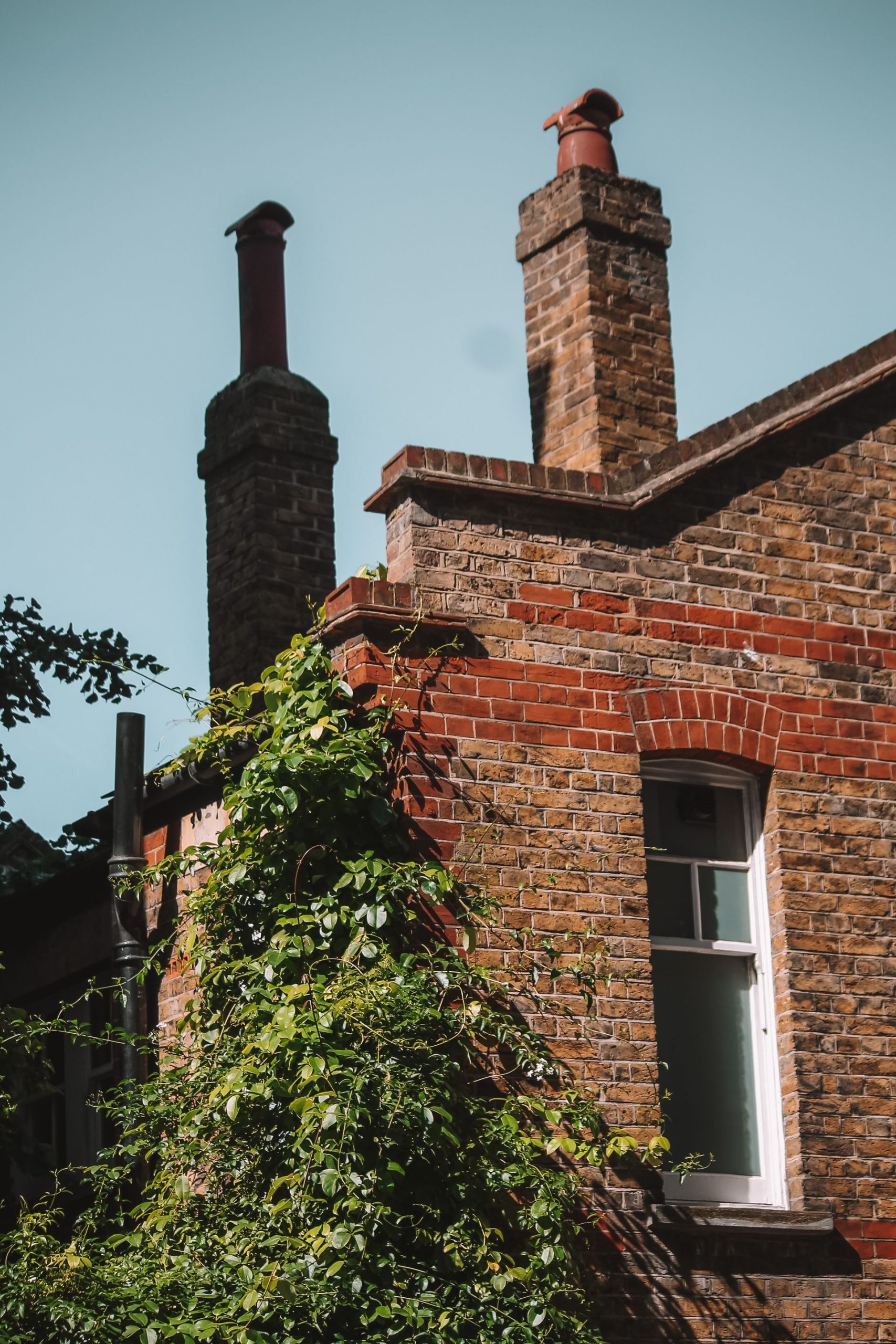 Brick house facade with ivy and two chimneys