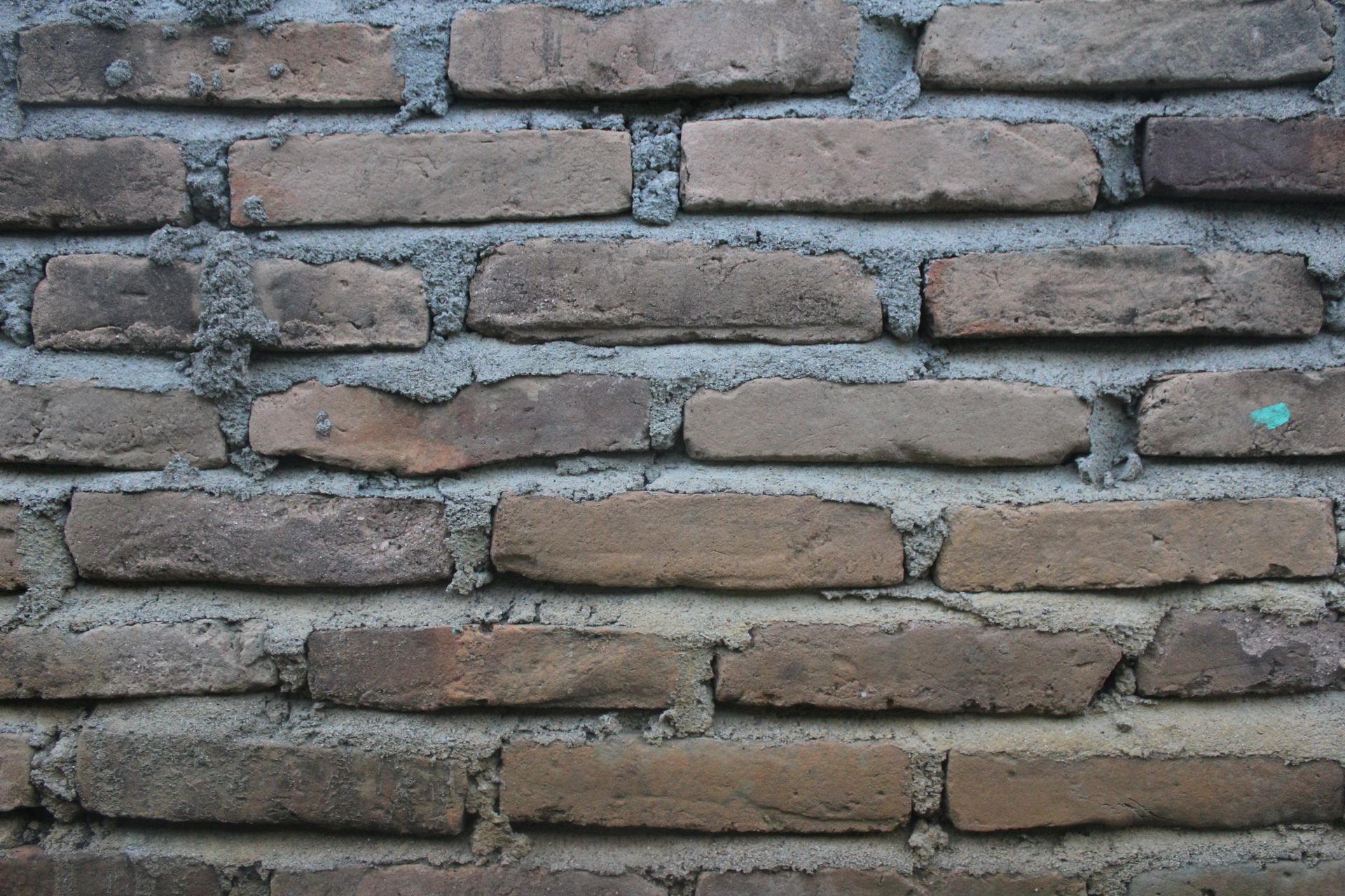 Weathered red brick wall with grey mortar joints
